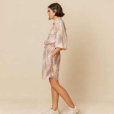 Mulher com vestido curto e ténis brancos em fundo bege