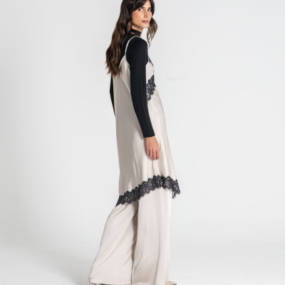 Conjunto feminino com blusa preta e saia creme com renda preta em fundo branco.