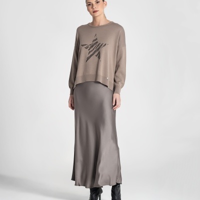 Mulher com camisola bege com estrela, saia cinzenta comprida e botas pretas