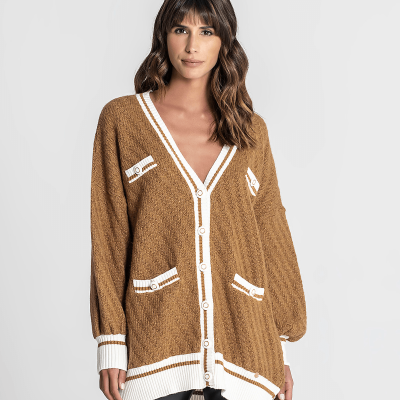 Casaco comprido de malha castanho com detalhes brancos nas bordas e botões, usado por mulher.