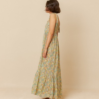 vestido longo feminino floral amarelo e verde com sandálias castanhas em fundo bege
