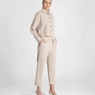 Mulher com camisa e calças bege e sapatos altos