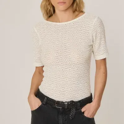 Mulher com camisola branca perfurada e calças pretas com cinto