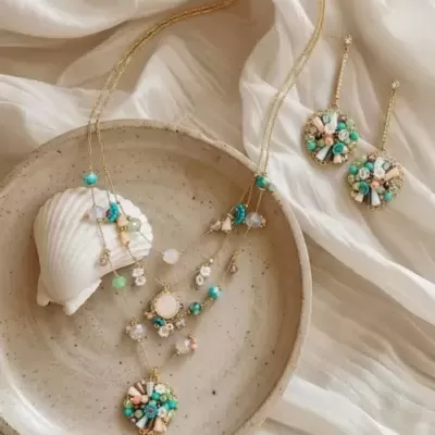 Conjunto de bijutaria com colar e brincos coloridos sobre prato cerâmico e tecido branco