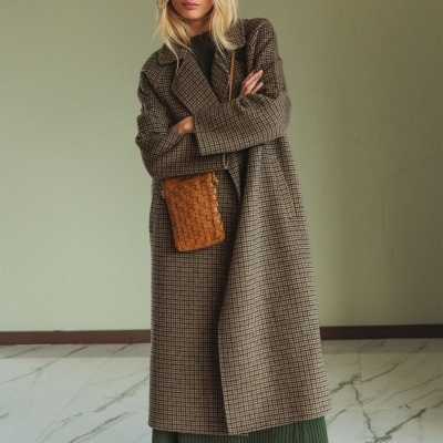 Mulher com casaco xadrez castanho, vestido verde e mala castanha com padrão trançado