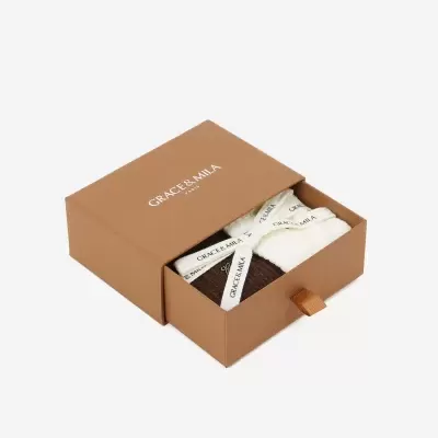 Caixa castanha com texto GRACE & MILA com peças de tecido dentro