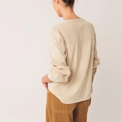 Blusa bege de manga comprida vista de costas com calças castanhas