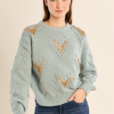 Camisola de malha azul clara com bordados em lantejoulas douradas e jeans azul escuro