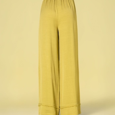 Calças largas amarelo mostarda com cinto castanho num fundo amarelo claro