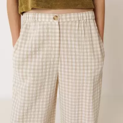 Calças compridas às quadrículas bege e branco com cintura elástica e botãodo