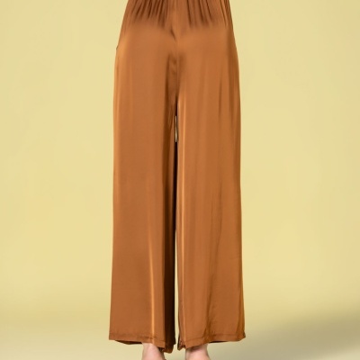 Calças largas castanhas em tecido acetinado com cintura elástica vistas de costas