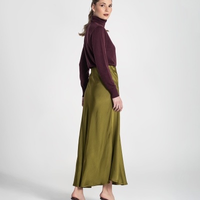 Mulher com camisola vinho e saia verde acetinada com sapatos de salto