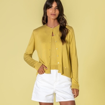 Mulher com cardigan amarelo e calções brancos em fundo amarelo