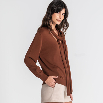 Mulher de perfil com camisola castanha e calções beje