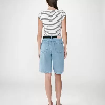 Mulher de costas com t-shirt às riscas, bermuda de ganga e sandálias.