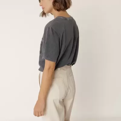 Mulher de perfil com t-shirt cinza e calças bege