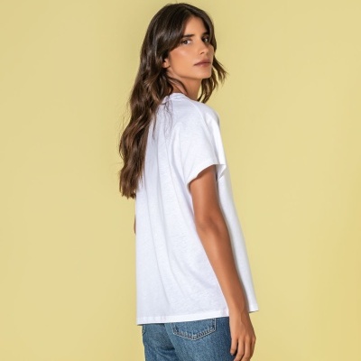 Pessoa de costas com t-shirt branca e calças de ganga azuis em fundo amarelo