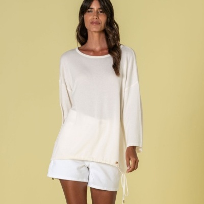 Mulher com camisola branca de manga comprida e calções brancos em fundo amarelo claro