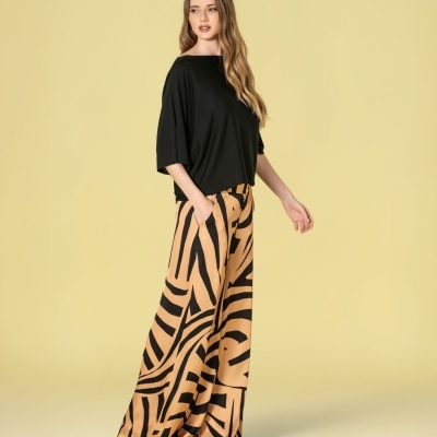 Mulher com blusa preta e calças largas bege com padrão abstrato preto