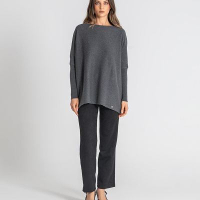 Mulher com camisola cinzenta e calças pretas em fundo branco