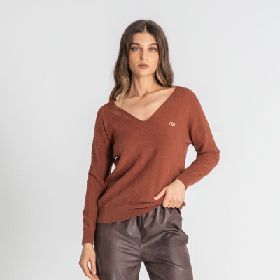 Camisola castanha de malha com padrão em relevo e logótipo dourado, usada com calças de couro castanho.