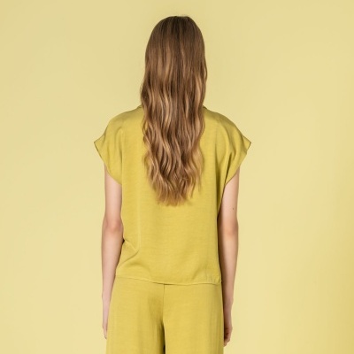 Pessoa de costas com conjunto amarelo composto por camisola de manga curta e calças largas.