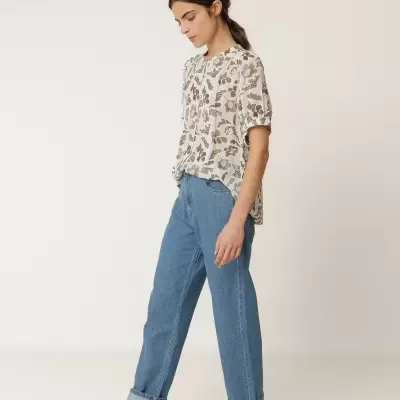 Mulher com blusa floral, calças de ganga e sandálias castanhas