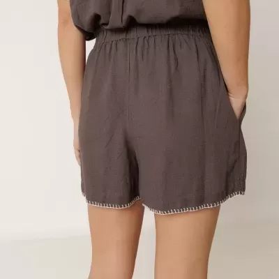 Calções castanho escuro com cintura elástica e bainha com costura branca vista de trás.