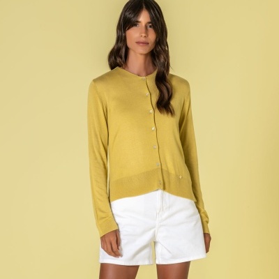 Mulher a vestir cardigan amarelo e calções brancos sobre fundo amarelo