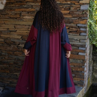 Casaco longo azul e bordô em parede de pedra