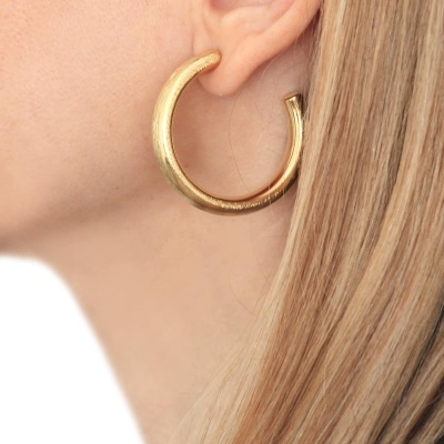 Brinco argola dourado com textura rugosa em orelha feminina loira
