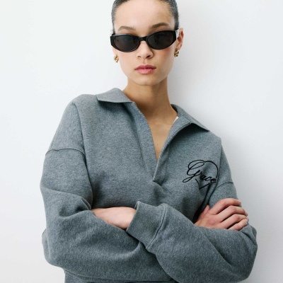 Mulher com sweatshirt cinzenta com bordado Grace e óculos de sol pretos