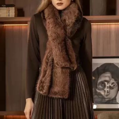 Mulher com lenço castanho de pele e vestido castanho, em ambiente interior com estante de madeira