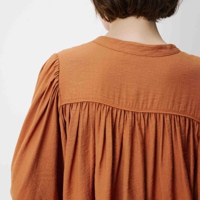 Vista das costas de uma blusa ou vestido cor de ferrugem com pregas e mangas franzidas