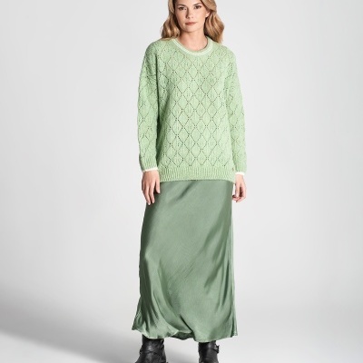 Mulher com camisola verde clara de malha e saia verde escura com botins pretos