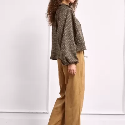 Mulher com blusa de padrão castanho e calças largas castanhas com ténis castanhos