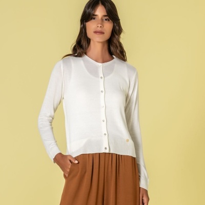 Mulher com cárdigan branco de malha fina e calças castanhas largas
