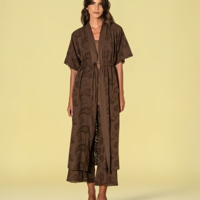 Conjunto feminino castanho com padrão bordado e cinto fino, composto por kimono e calças largas com barra rendada, sandálias pretas de salto fino.