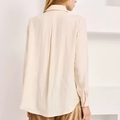Blusa creme feminina vista de costas com calças castanho claro num fundo branco
