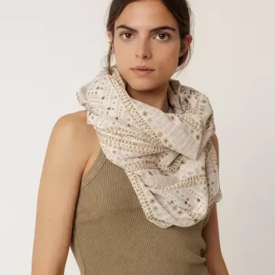 Lenço leve creme com padrões geométricos em castanho e laranja ao pescoço.