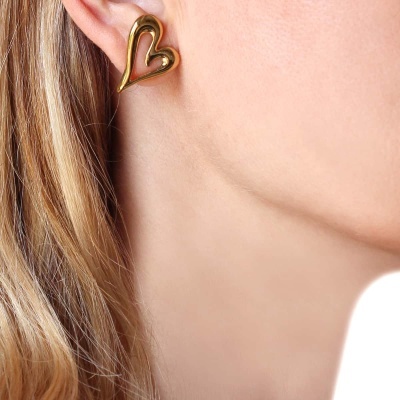Brinco dourado em forma de coração na orelha de pessoa com cabelo loiro