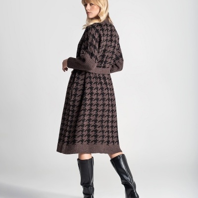 Mulher de costas a usar casaco longo de malha com padrão pied de poule castanho e preto e botas pretas de cano alto.