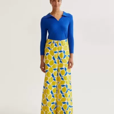 Mulher com camisola azul de malha e calças largas estampadas de limões