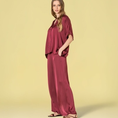 Conjunto pijama acetinado bordô com sandálias pretas em fundo amarelo