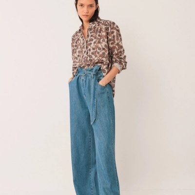 Mulher com camisa floral castanha e bege e calças de ganga largas azuis