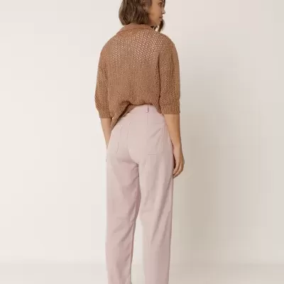 Mulher de costas com calças rosa claro e camisa de malha castanha