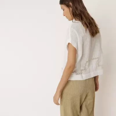 Mulher de costas com blusa branca e calças bege