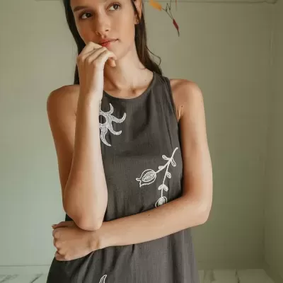 Vestido cinza escuro com bordados brancos usado por mulher