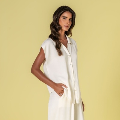 Mulher com camisa branca sem mangas e saia branca