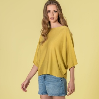 Mulher com camisola amarelo-mostarda e calções de ganga azul